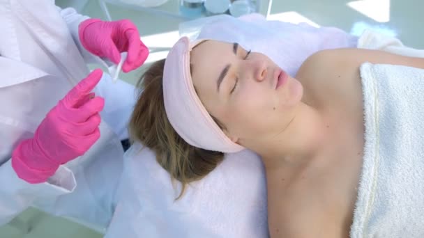 Kosmetolog šťourání akné na ženskou tvář pomocí jehly a otírání bavlněné podložky. — Stock video