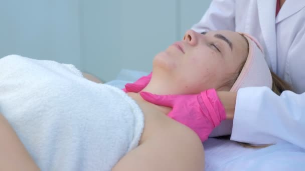 Масаж шиї та обличчя для молодої жінки лікарем-косметологом у клініці . — стокове відео