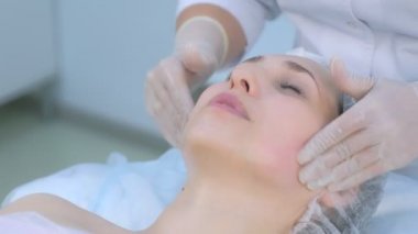 Kozmetik uzmanı güzellik kliniğinde kadınların yüzüne masaj yapıyor..
