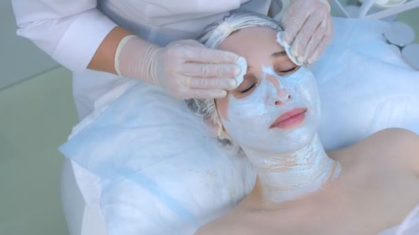 Beautician wipes mask from womans face using cotton pads in beauty clinic. — Stock Video