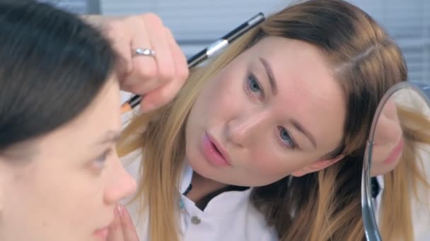 Cosmetolog care face procedura sprâncenelor nuante pentru o femeie tânără din clinica de înfrumusețare . — Videoclip de stoc