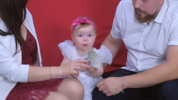 Mamá está tratando de ponerse gorra de fiesta en su hija bebé en su primer cumpleaños . — Vídeos de Stock