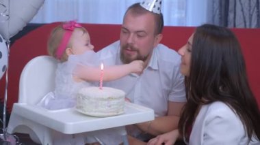 Aile portresi anne, baba ve bebek ilk doğum gününde pasta ve mumla.
