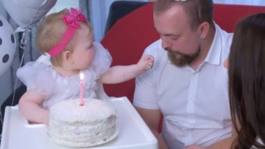 Aile portresi anne, baba ve bebek ilk doğum gününde pasta ve mumla.
