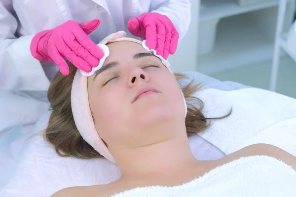 Cosmetologi mani peeling pulire le donne viso batuffoli di cotone in clinica di bellezza . — Foto Stock