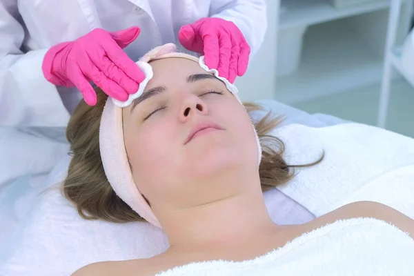 Cosmetólogos manos pelando limpiando mujeres cara algodón almohadillas en clínica de belleza . — Foto de Stock