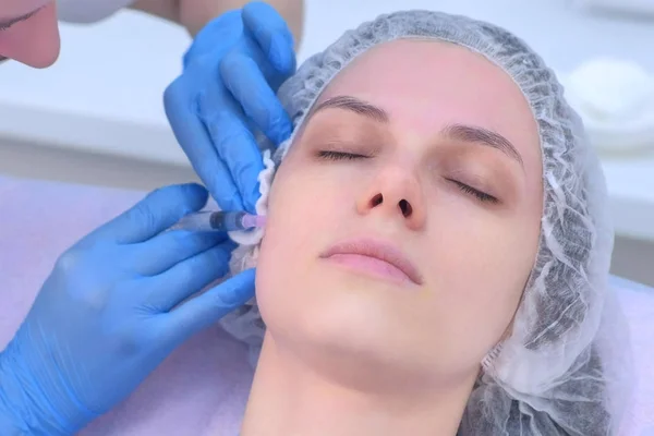 Doctor is making multiple injections in womans face skin during mesotherapy.