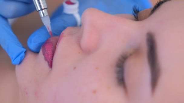 Beautician εφαρμογή μόνιμη μακιγιάζ για τα χείλη κορίτσι χρησιμοποιεί μηχανή τατουάζ, closeup. — Αρχείο Βίντεο