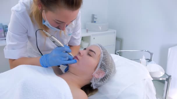 Cosmetoloog het maken van lippen microblading procedure voor meisje met behulp van tattoo machine. — Stockvideo