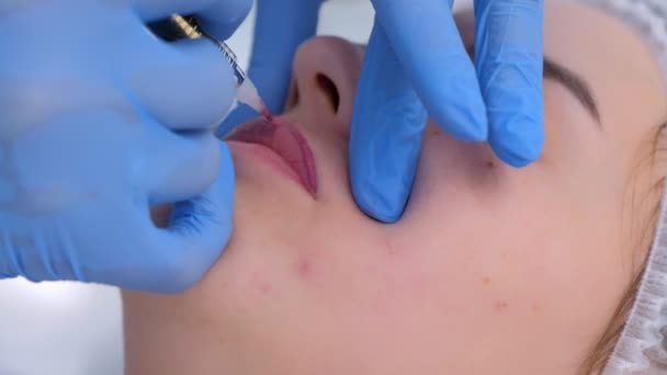 Beautician is het toepassen van permanente make-up op vrouwelijke lippen met behulp van tattoo machine. — Stockvideo