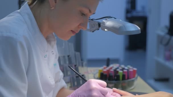 Мастер маникюра рисует ногти гель Шеллак с помощью кисти в клинике красоты. — стоковое видео