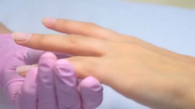 Manikür ustası elektrikli çivi matkabı kullanarak müşteri için manikür yapıyor.