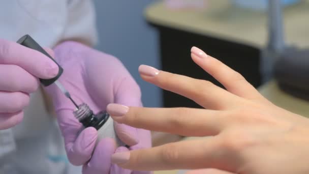 Manicurista maestro está pintando las uñas de los clientes con capa superior, las manos de cerca. — Vídeo de stock