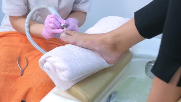 Fußpflegerin entfernt Nagelhaut aus Zehen von Kunden mit elektrischem Nagelmaschine.