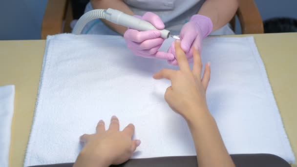 Mujer manicurista elimina el esmalte de goma laca utilizando la máquina de manicura, las manos de cerca. — Vídeo de stock