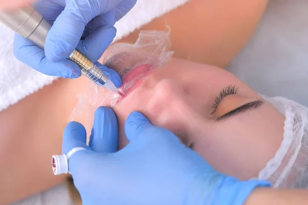 Cosmetologist making lips microblading procedure for girl using tattoo machine. — Stock Photo, Image