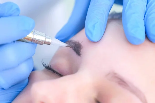 Cosmetoloog maken wenkbrauwen microblading procedure in schoonheidssalon voor vrouw. — Stockfoto