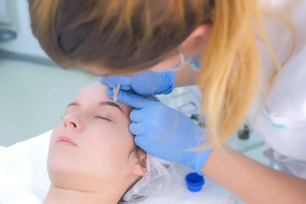 Cosmetoloog maken wenkbrauwen microblading procedure in schoonheidssalon voor meisje. — Stockfoto