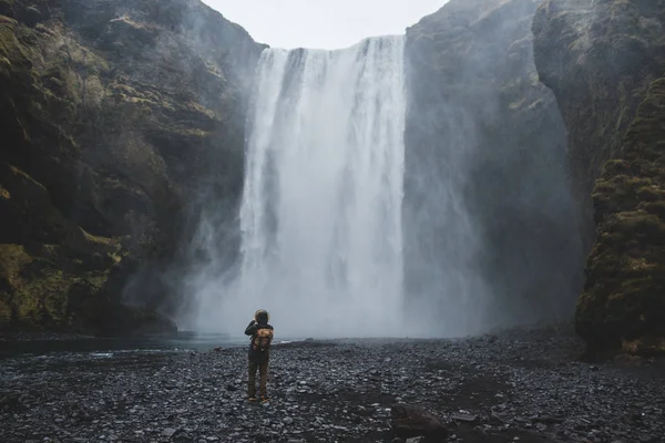 O homem fica no fundo da cachoeira Skogafoss — Fotografia de Stock