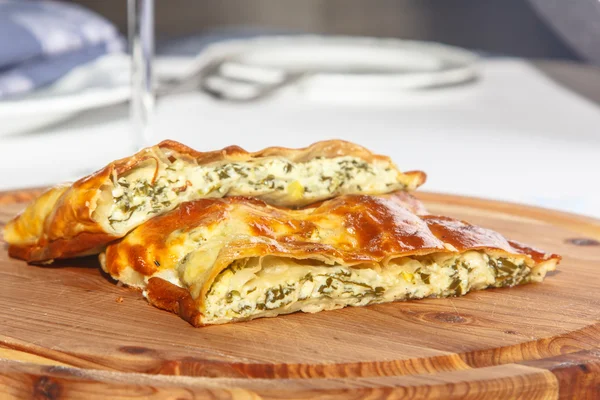 Torta di pasta sfoglia con spinaci e formaggio su una tavola di legno . — Foto Stock