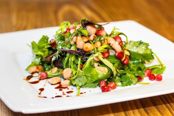 Salad with boiled beans, greens with pomegranate seeds. A tradit — Stock Photo, Image