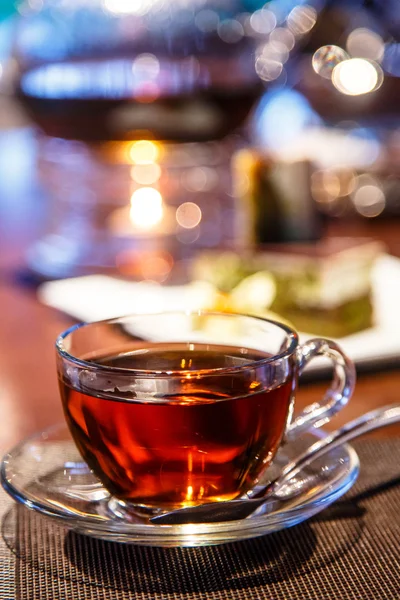 Svart te i glas Cup och tekanna med ett ljus står på — Stockfoto