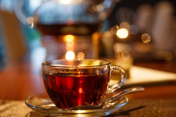 Black tea in glass Cup and  teapot with a candle stands on