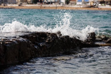 Dalgalar kayalar ve su sıçramalarına bölünürler. Akşam.