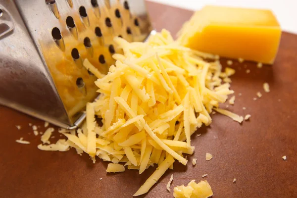 Cheese rubbed on a grater on a dark Board. — Stock Photo, Image