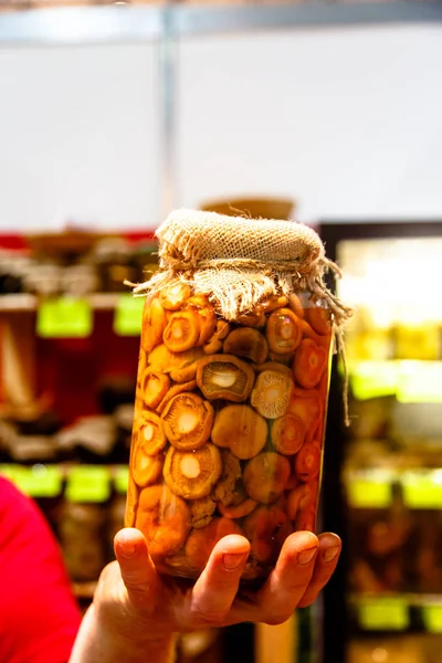 Rosyjskie specjały - grzyby marynowane w szklanym słoiku w dłoni — Zdjęcie stockowe