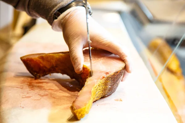 Der Verkäufer auf dem Markt zerteilte den geräucherten Fisch in Steaks. — Stockfoto