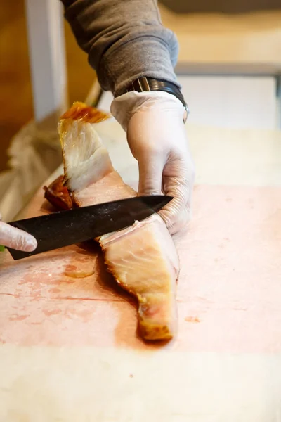 El vendedor en el mercado cortó el pescado ahumado en filetes . —  Fotos de Stock