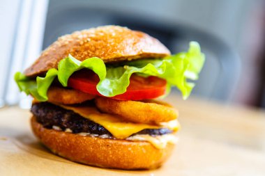 Hamburger peyniri, biftek, soğan halkaları ve salata ile.
