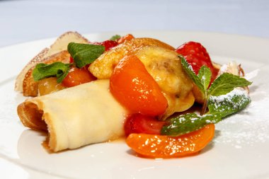 Krep meyve ile pudra şekeri serpilir ve üzerinde meyveleri vardır 