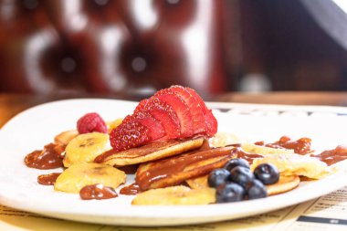 Krep yerken üzerine çikolata sos ile yalan çilek dilimlenmiş.