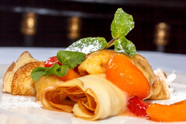 Krep meyve ile pudra şekeri serpilir ve üzerinde meyveleri vardır 