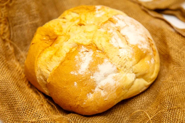 Zelfgemaakte ronde brood uit tarwemeel ligt op ruwe doek.. — Stockfoto