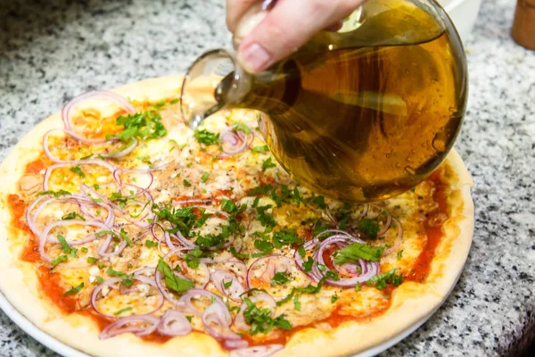 Пицца готовит. Повар наливает приготовленную пиццу оливковым маслом . — стоковое фото
