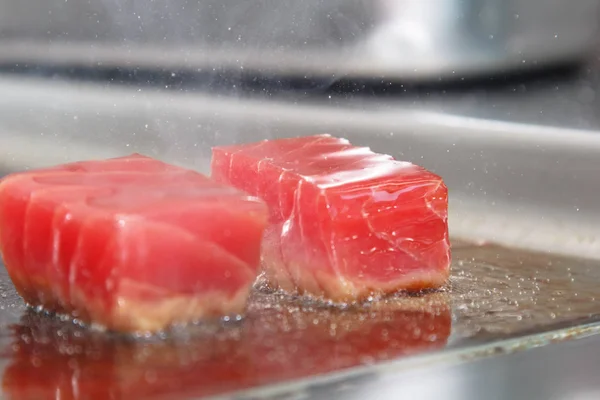 Plakjes rauwe tonijn gebrand op de grill. Druppels olie vliegen — Stockfoto