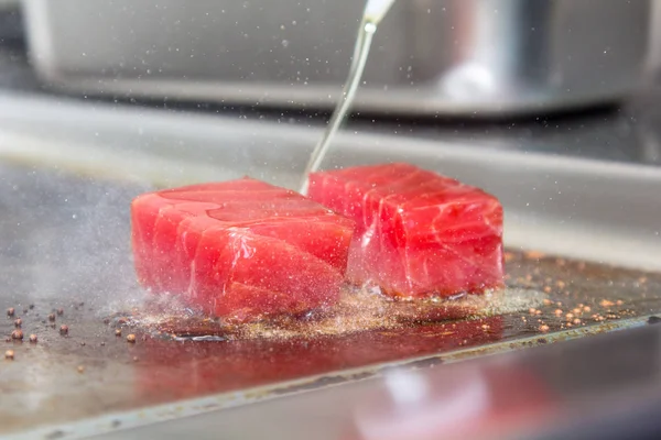 Plakjes rauwe tonijn gebrand op de grill. Druppels olie vliegen — Stockfoto