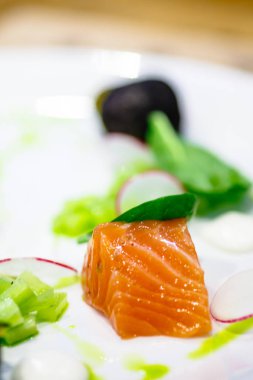 Tuzlu dilim somon üzerinde salatalık ve turp plakadır. Macr