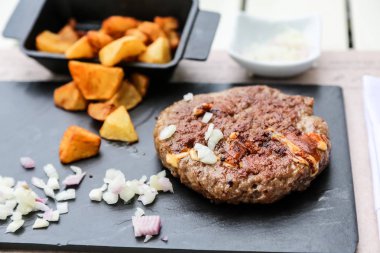 Üzerine soğan ve patates kızartması ile sığır kıyılmış biftek ızgara bir