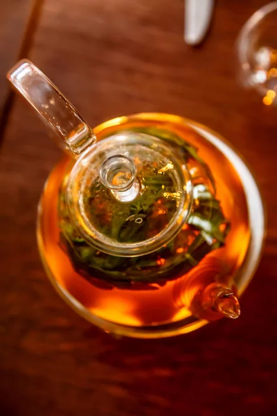 Te i en glas tekanna på ett stativ med ett ljus. — Stockfoto