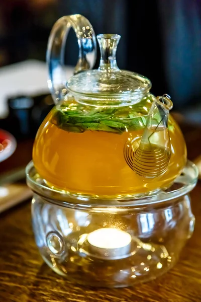 Čaj ve skleněné konvici na podstavec se svíčkou. — Stock fotografie