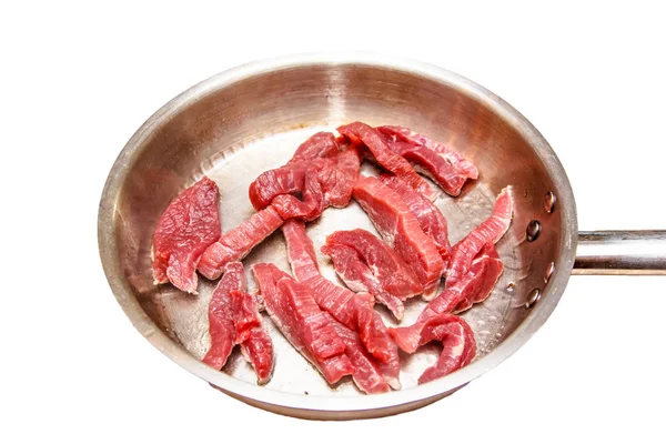 Ham sığır eti dilim üzerinde çelik bir tavada kavrulmuş. İzoleli.