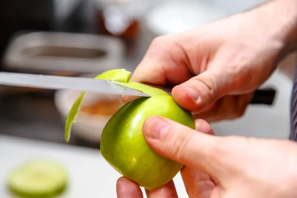 Повар чистит кожу яблока ножом . — стоковое фото