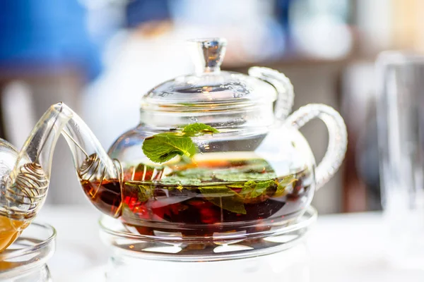 Chá com folhas de hortelã em um bule de vidro com uma vela . — Fotografia de Stock