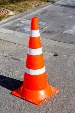 Kaldırım üzerinde acil çizgili koni duran.