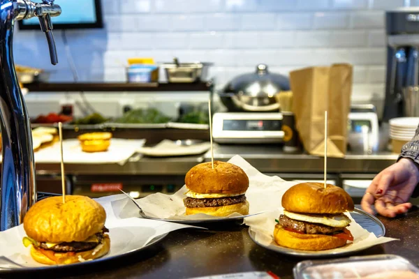 Tres hamburguesas están en el mostrador de un restaurante, comida rápida . —  Fotos de Stock