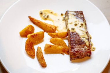 Kızarmış patates dilimleri ve biftek ve biber sosu.